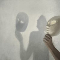 surreal shadow on the wall of a person who takes off the mask from his face, concept of truth and fiction
